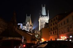 cars parked on the side of a street in front of tall buildings with spires at night