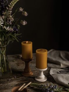 two candles sitting on top of a table next to a vase with flowers in it