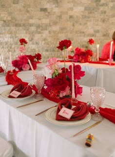 the table is set with red and pink flowers