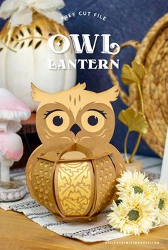 an owl lantern sitting on top of a wooden table next to flowers and other decorations