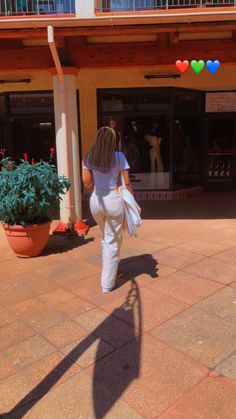 a woman is walking down the sidewalk in front of a building with balloons on it