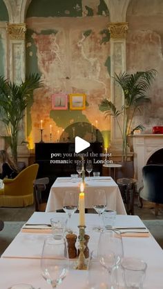 a dining room with white table cloths and candles on top of the long tables