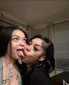 two women are posing for the camera and one is sticking her tongue out to kiss the other