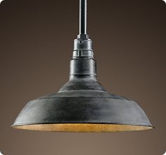 an industrial style pendant light hanging from a ceiling fixture in a dark room with a brown wall behind it