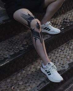 a person sitting on some steps with their legs covered in black and white tattoo designs