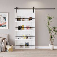 a living room with a white book shelf next to a plant