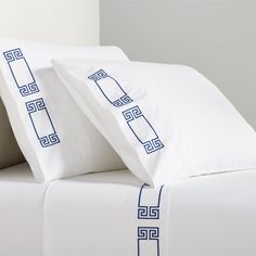 two white pillows with blue greek border on a bed