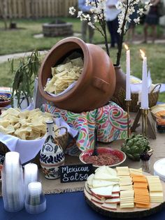 a table topped with lots of food next to a vase filled with flowers and candles