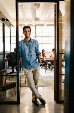 a man standing in an open doorway with his hands in his pockets and smiling at the camera