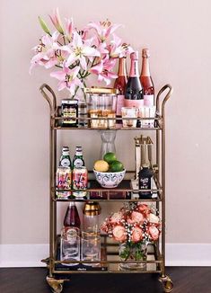 a gold bar cart filled with drinks and flowers