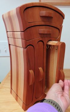 a person is opening the door to a wooden cabinet that has been made from wood