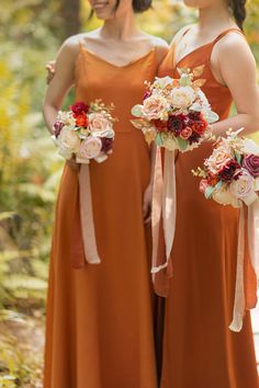 two bridesmaids in orange dresses holding bouquets