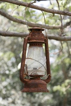 an old fashioned lantern hanging from a tree branch