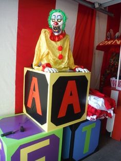 a clown statue sitting on top of blocks in front of a red and white striped wall