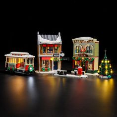 three small buildings with christmas lights and decorations on the front, two are made out of legos