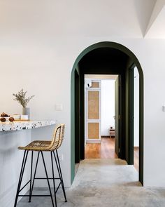 an archway leading into a kitchen with stools in front of it and a counter on the other side