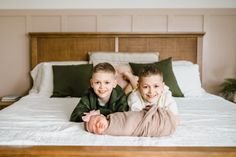 two young boys laying on a bed smiling at the camera with their arms around each other