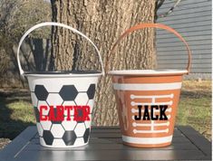 two buckets sitting on top of a table next to a tree