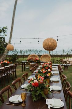 a long table is set with plates and place settings for an outdoor wedding reception at the beach