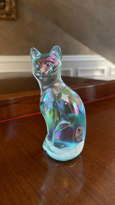 a glass cat sitting on top of a wooden table