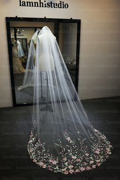 a wedding veil is on display in front of a mannequin's dress