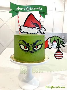 a green cake decorated with an angry grin face and santa claus hat on it's top