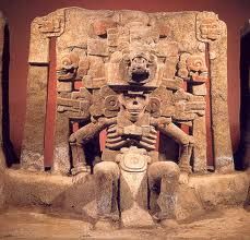 an ancient statue is sitting in front of a red wall