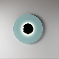 a round light that is on top of a white wall with a black hole in the middle