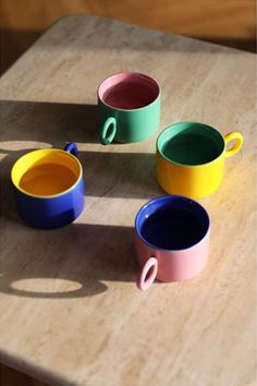 four different colored cups sitting on top of a wooden table