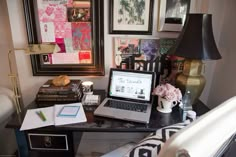 a laptop computer sitting on top of a desk next to a lamp and some pictures