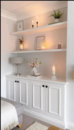 some white shelves with candles and flowers on them