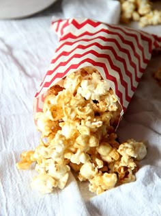 a bag filled with popcorn sitting on top of a white table cloth next to some cookies