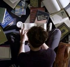 a person sitting on the floor surrounded by books