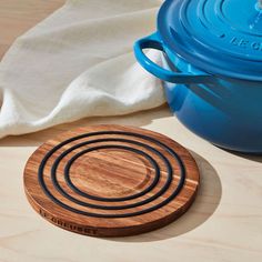 a wooden coaster sitting on top of a table next to a blue casserole