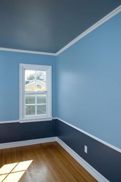 an empty room with blue walls and wood floors