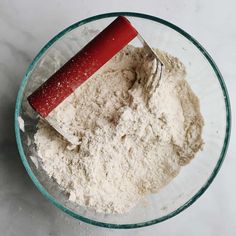 a glass bowl filled with flour and a whisk