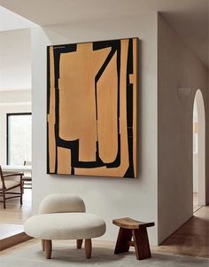 an abstract painting hangs on the wall next to a foot stool