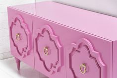 a pink sideboard with gold handles on it