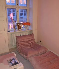 a futon bed sitting in front of a window next to a table with a magazine on it