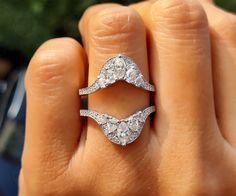 a woman's hand with two diamond rings on top of her finger and the other hand holding an engagement ring