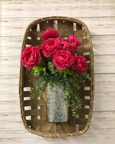 a vase filled with red flowers sitting on top of a wooden shelf next to a wall