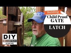 a man in a green shirt and blue hat standing next to a wooden structure with the words build proof gate latch on it