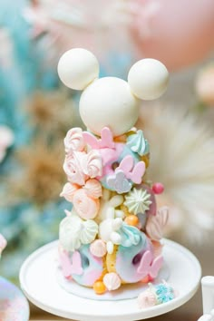 a mickey mouse cake is decorated with pastel colors and decorations on a white plate