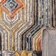 the corner of an area rug with different colors and patterns on it, including blue, yellow, red, orange, and grey