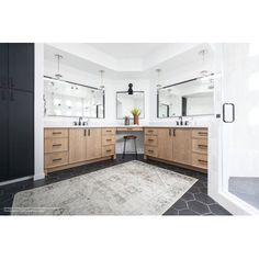 a bathroom with two sinks, mirrors and a rug on the floor in front of it