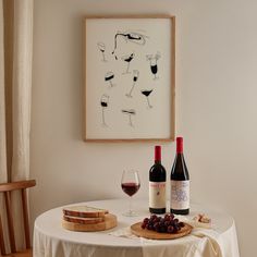 two bottles of wine sit on a table with cheese and bread