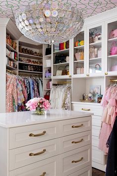 a closet with lots of clothes and shoes on it's shelves, along with a chandelier hanging from the ceiling