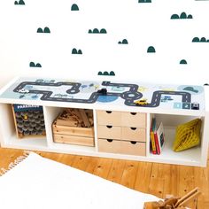 a child's playroom with toy cars on the wall and storage drawers below