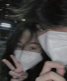 two people wearing face masks and making peace signs