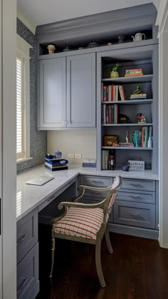 a desk and chair in a room with gray cupboards on either side of the desk